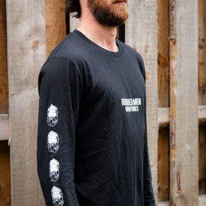 Man wearing black long sleeve tee with bearded men adventures logos in white.