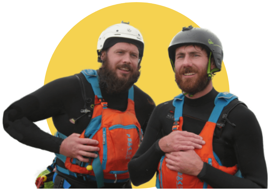 Two men wearing helmets and life vests with orange accents, standing against a yellow circle background.